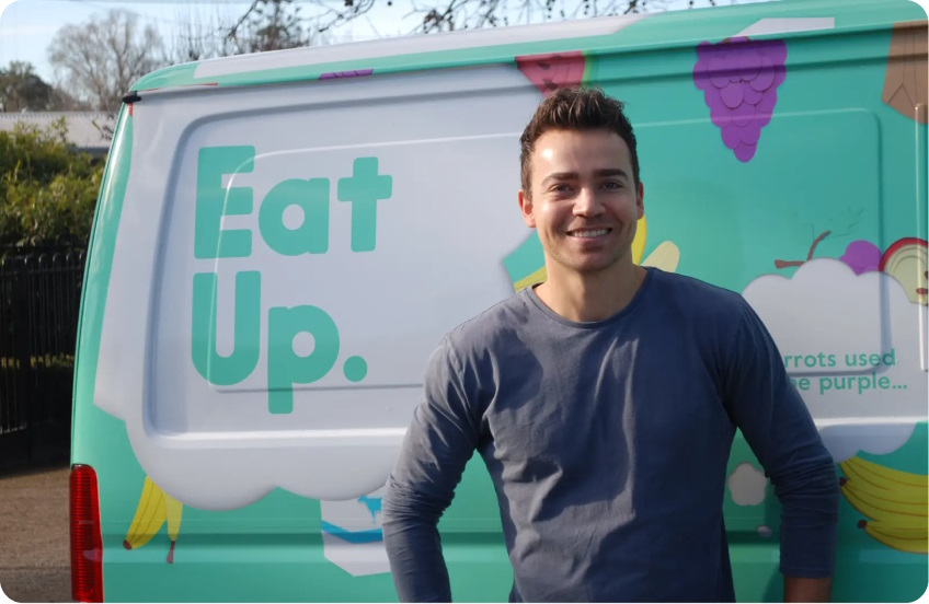 Man standing in front of van with Eat Up branding, smiling